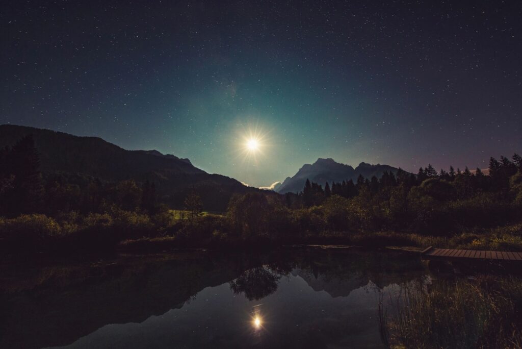 A full moon is setting over the mountains.