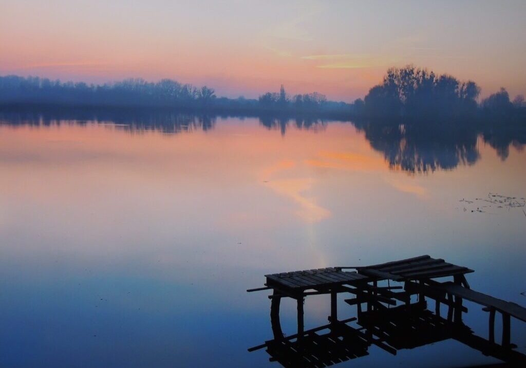 A dock on the water with trees in the background.