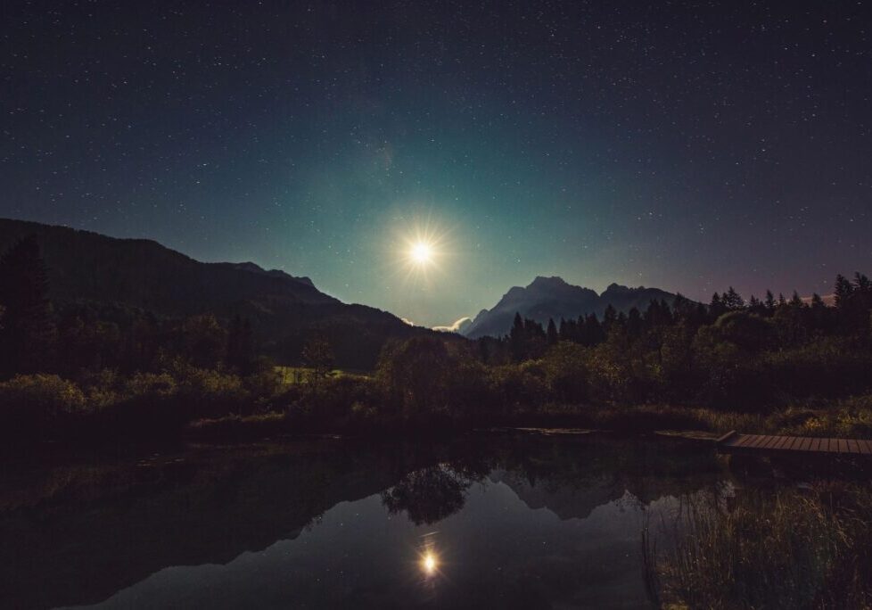 A full moon is setting over the mountains.